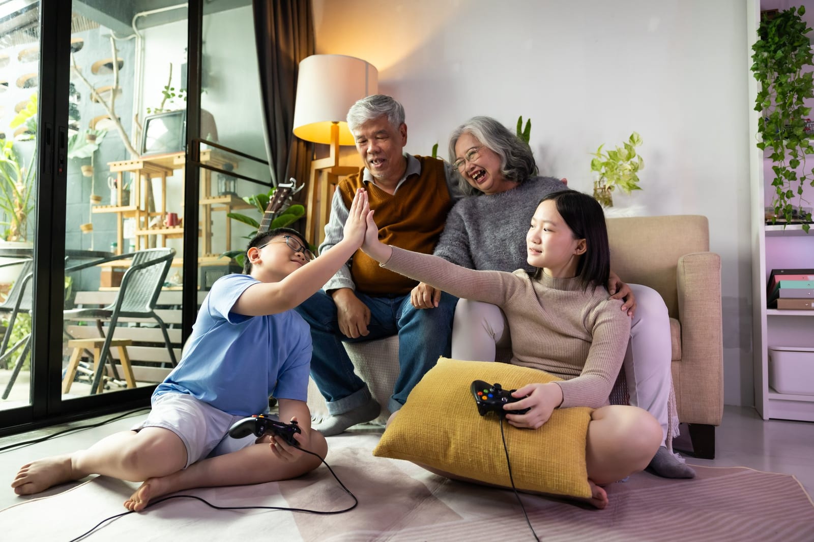 リビングでゲームを楽しむ三世代のアジア人家族