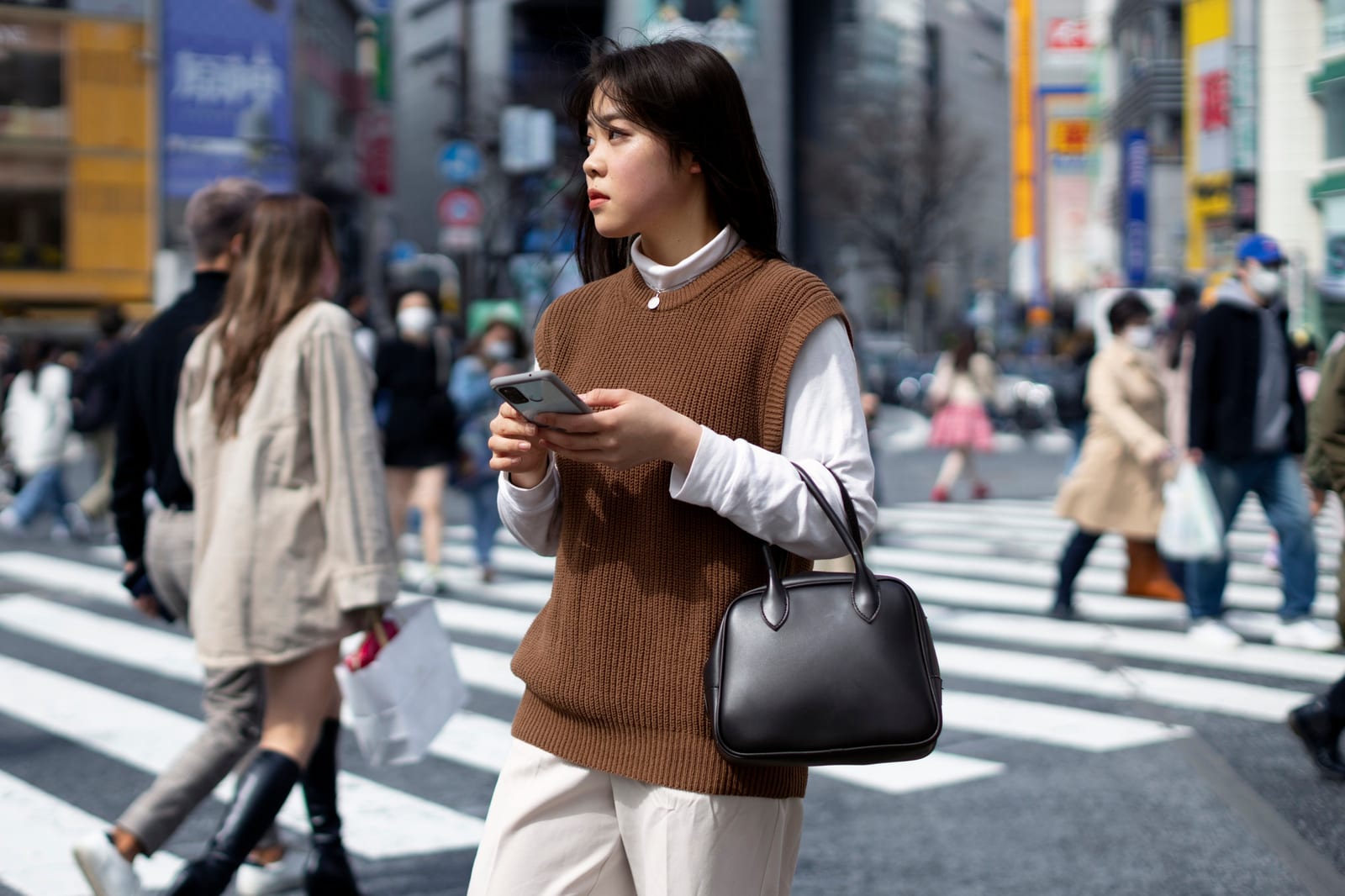 街角でスマートフォンを手にする若い日本人女性